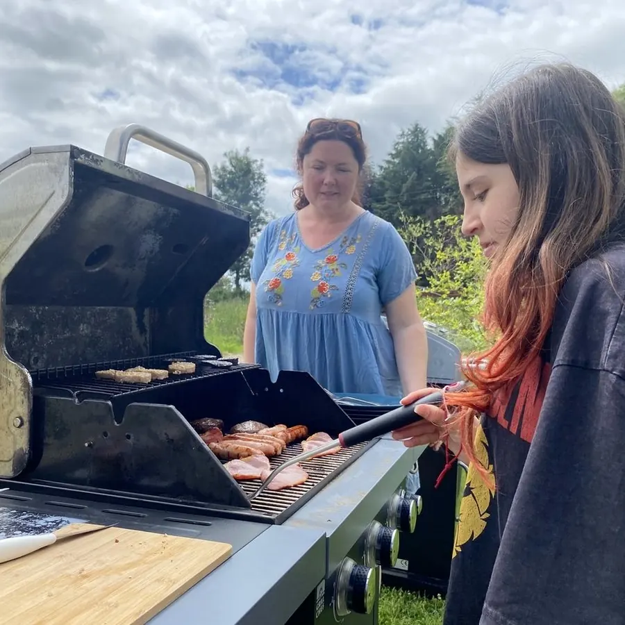 Student helping prepare a barbecue at C2