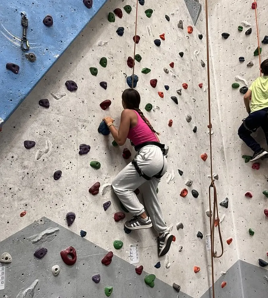 Student indoor rock climbing with safety equipment