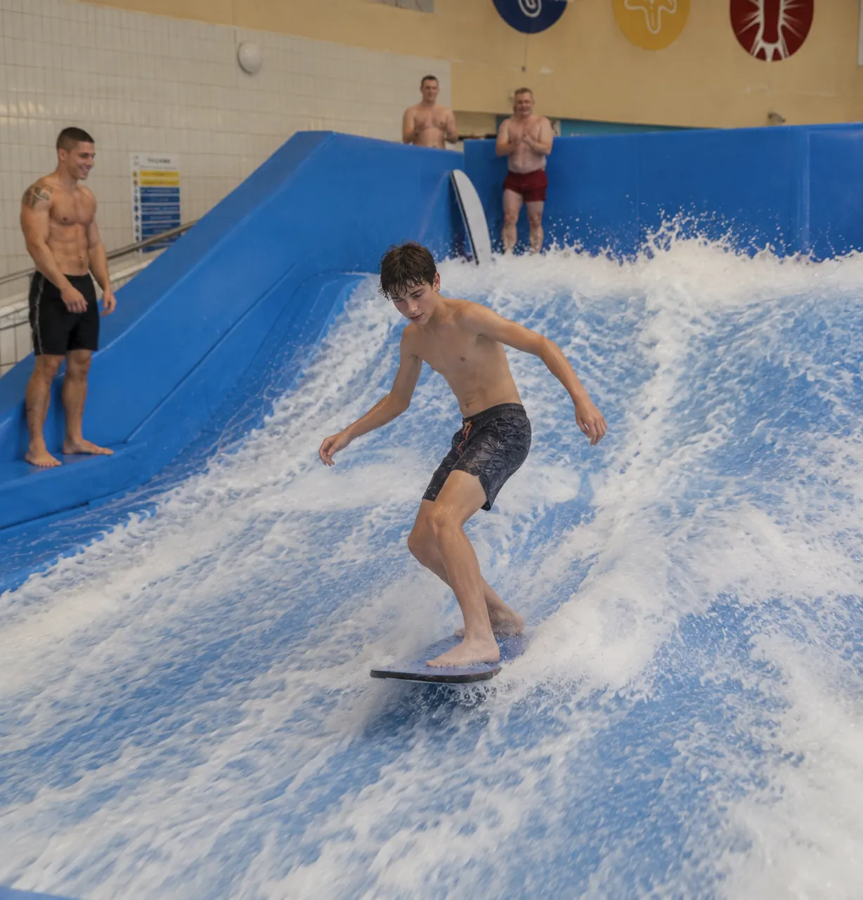 Teenager surfing on an indoor FlowRider at a water park